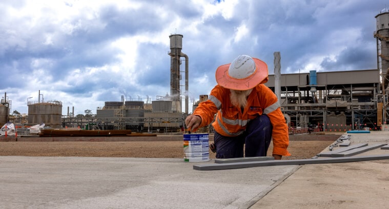 Worker painting protective coating on concrete